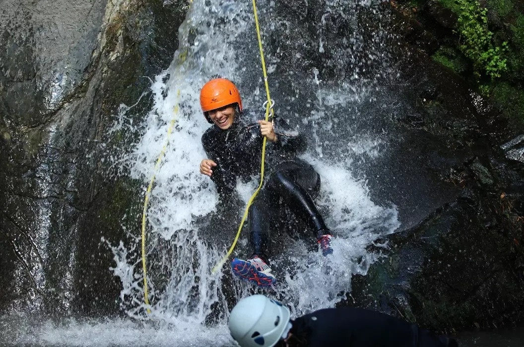 une personne portant un casque orange descend une cascade