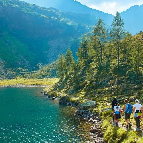 un grupo de personas camina junto a un lago en las montañas