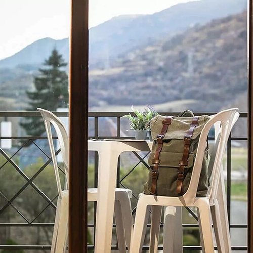 un balcón con una mesa y sillas y una mochila en la silla