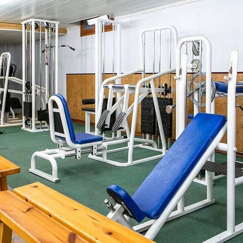 un gimnasio con muchos aparatos y bancos de madera