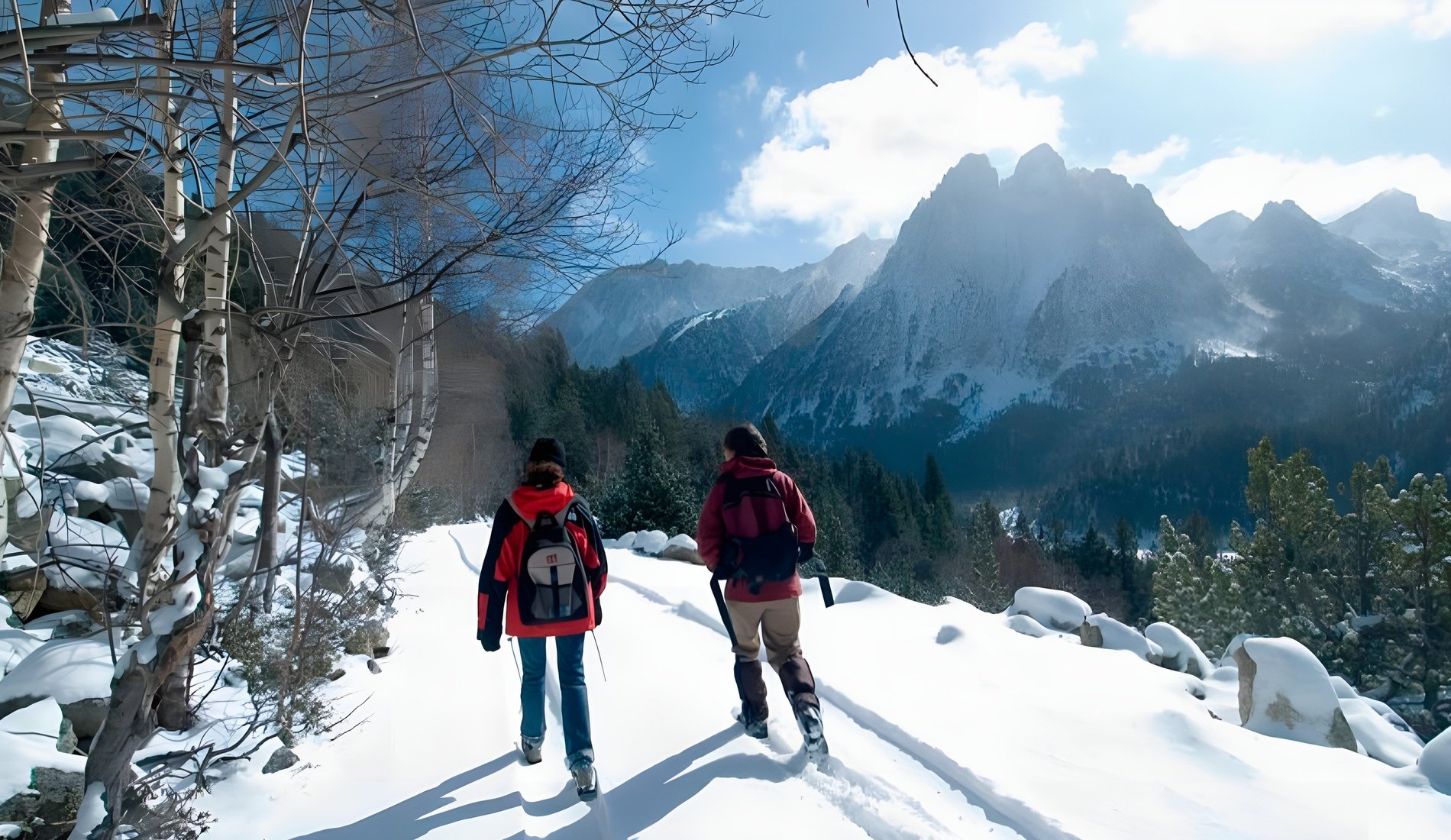 dos personas caminan por un sendero cubierto de nieve con montañas en el fondo