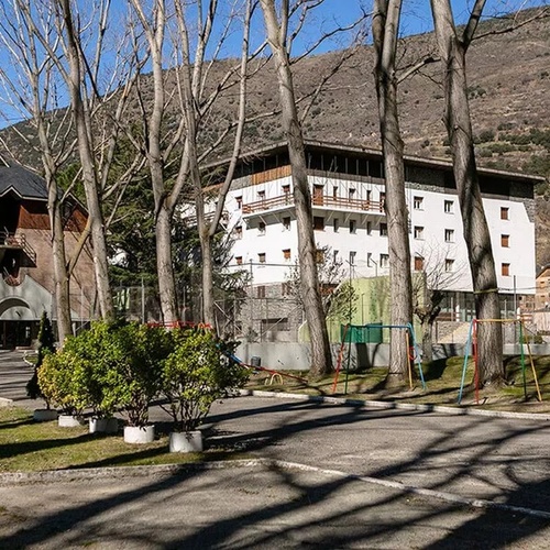 un gran edificio blanco está rodeado de árboles y arbustos