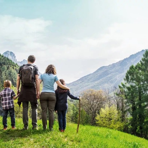 una familia con mochilas camina por un sendero en las montañas