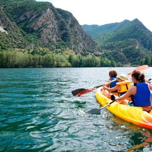 dos personas en kayak en un lago con montañas en el fondo