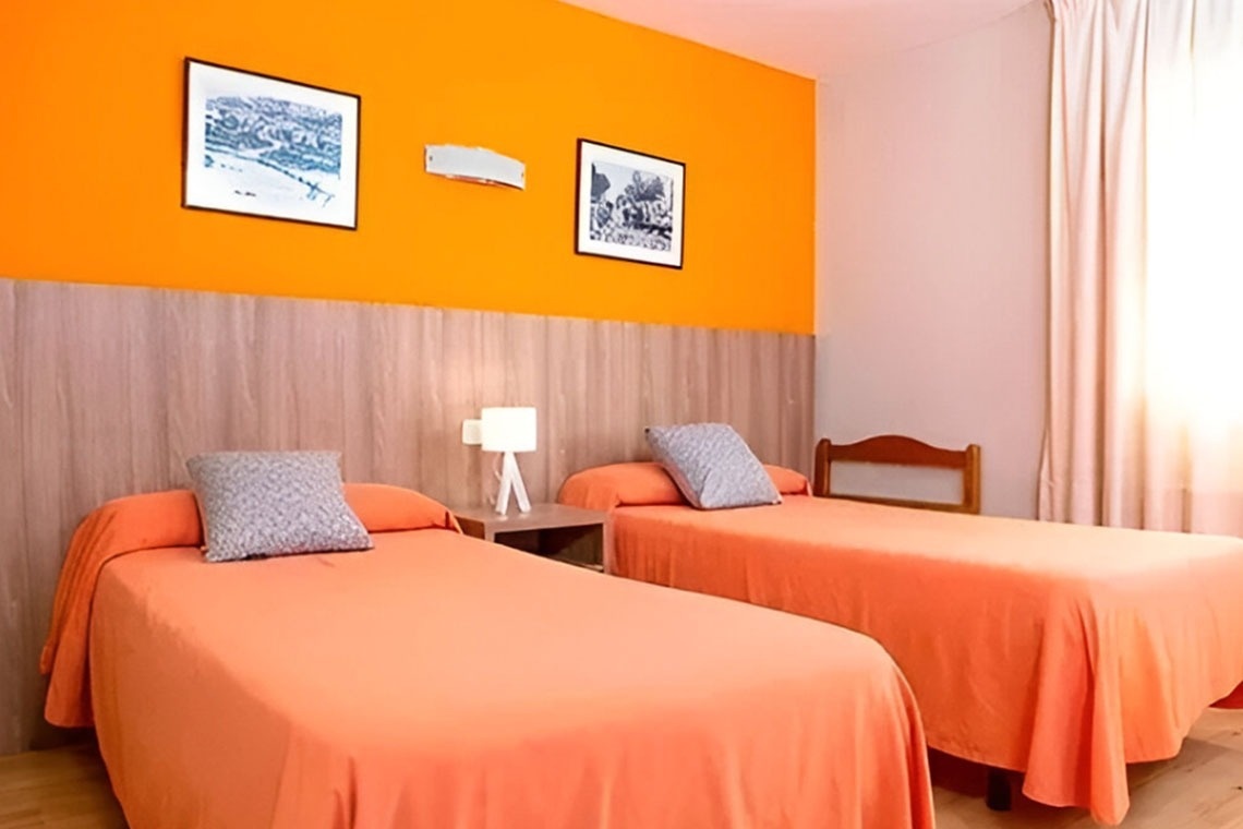 dos camas en una habitación con una pared naranja