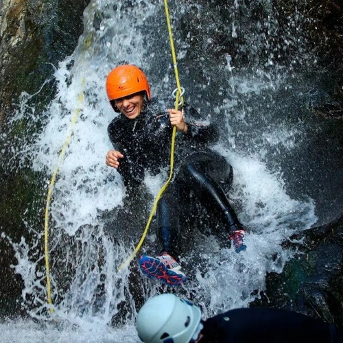 una mujer con un casco y una cuerda en una cascada