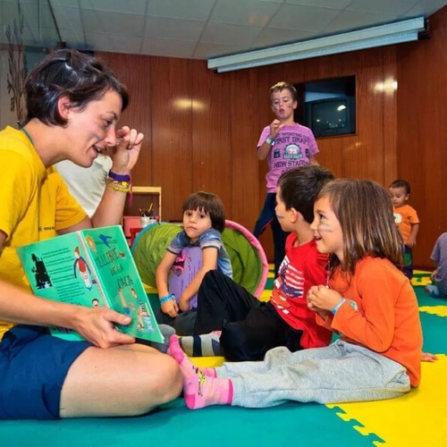 una mujer lee un libro a un grupo de niños