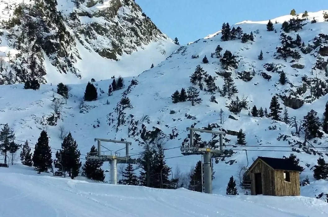 una pequeña cabaña de madera se sienta en la ladera de una montaña cubierta de nieve