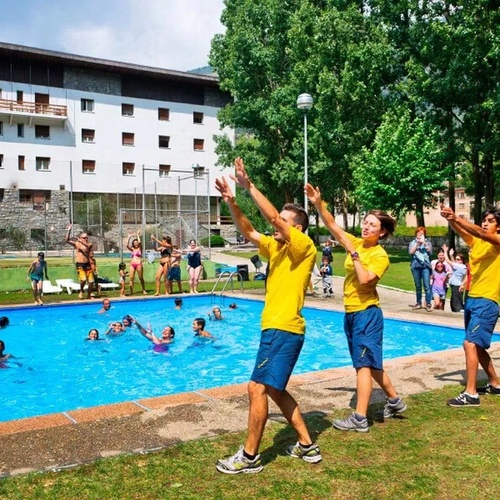 un grupo de niños en camisetas amarillas bailan junto a una piscina