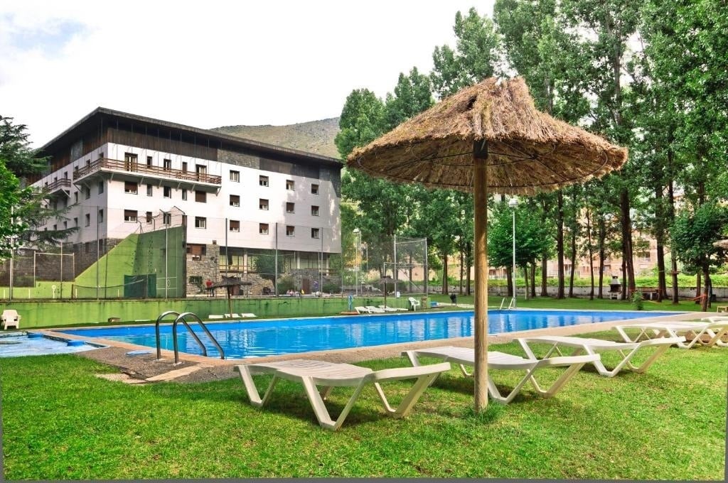 una piscina rodeada de sillas y un paraguas de paja