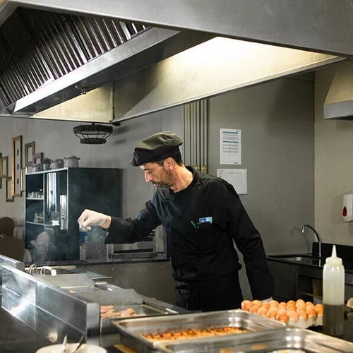 un chef travaille dans une cuisine avec une bouteille d' eau à côté de lui