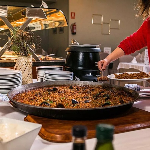 una mujer sostiene un plato de comida frente a una sartén de comida