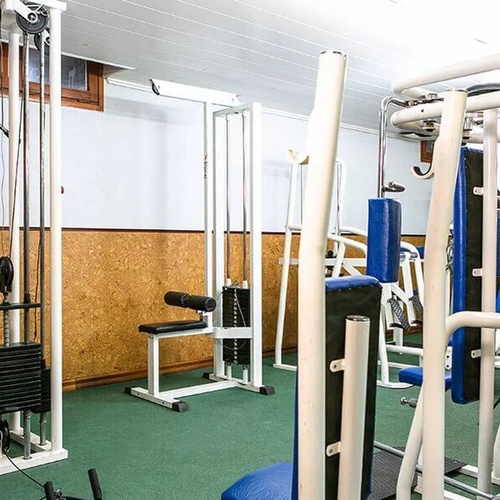 un gimnasio con muchos aparatos y una silla azul