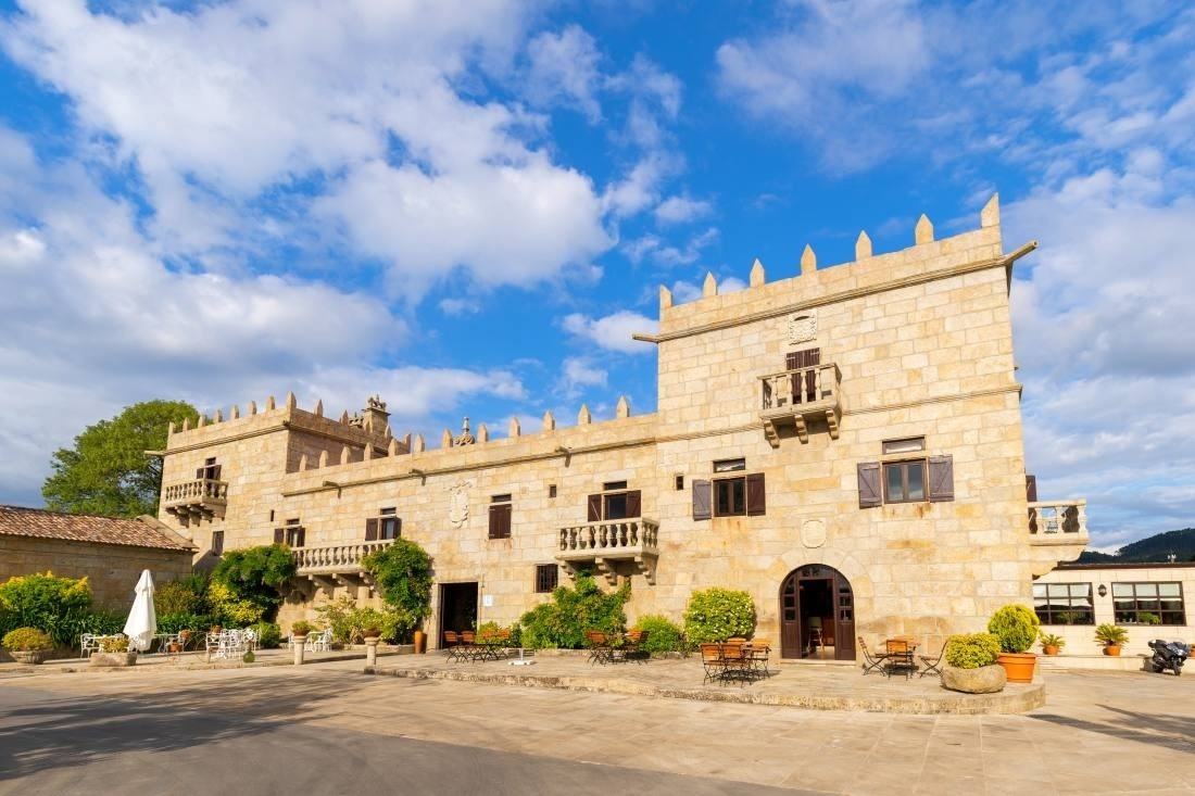 un gran edificio de piedra con balcones y mesas y sillas al frente