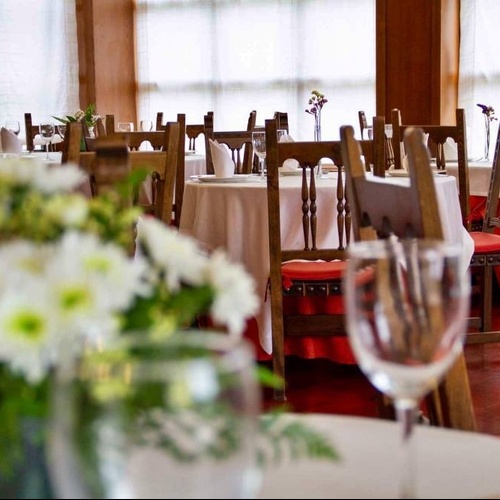 un restaurante lleno de mesas y sillas con un jarrón de flores en primer plano