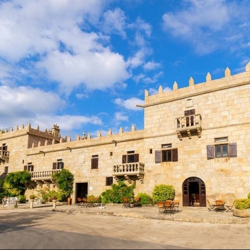 un gran castillo de piedra con mesas y sillas en el patio