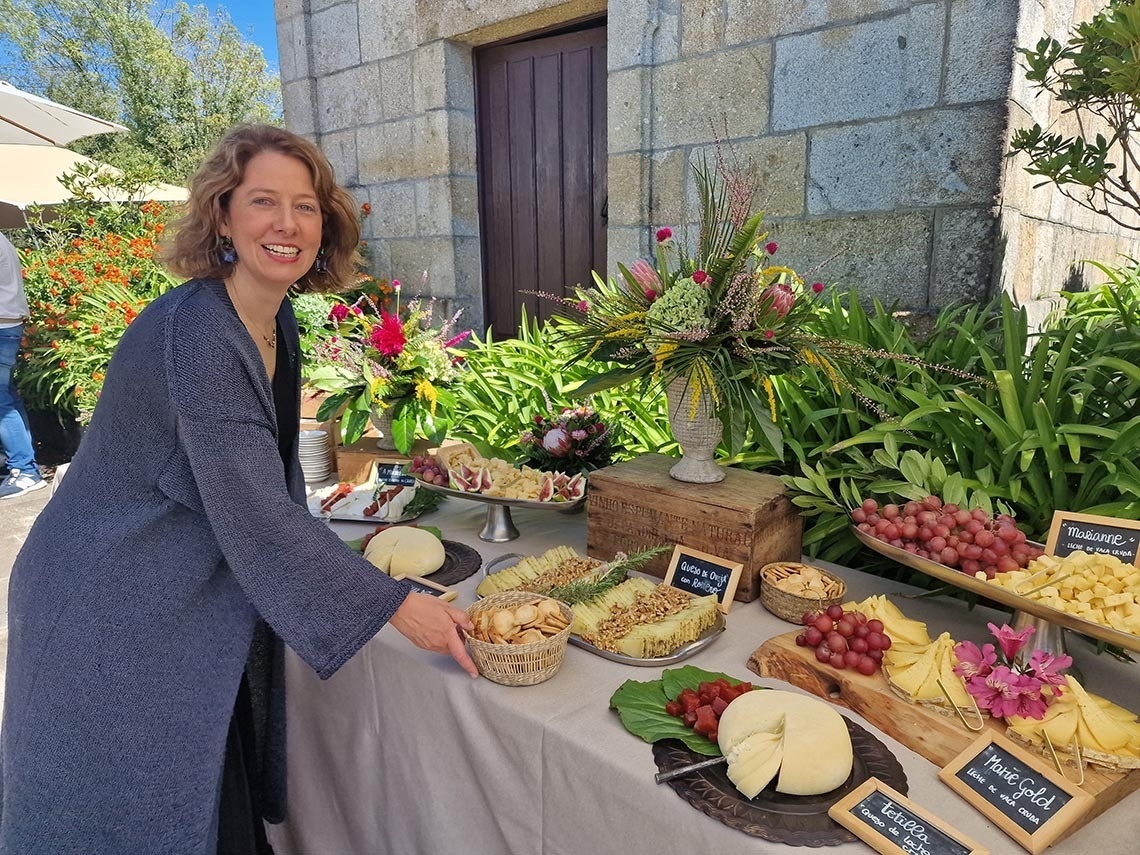 una mujer se para frente a una mesa de quesos y frutas