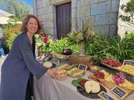 una mujer se para frente a una mesa de quesos y frutas