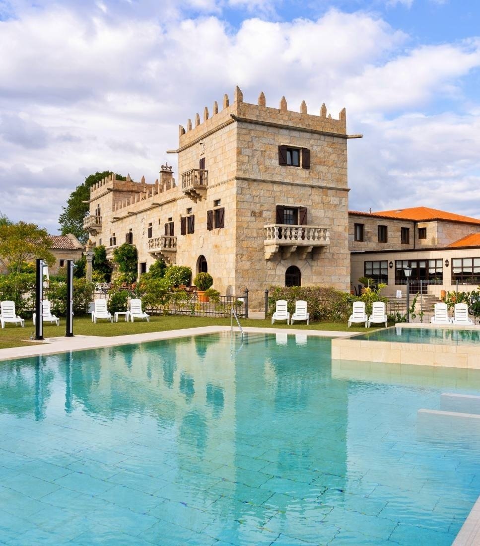 una piscina rodeada de césped verde y sillas blancas