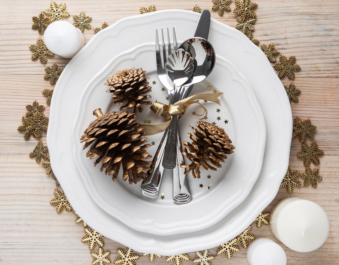 a white plate with silverware and pine cones on it