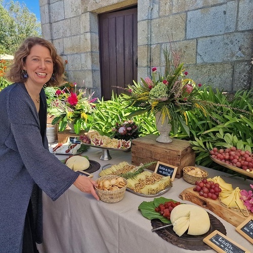 une femme se tient à côté d' une table remplie de fromages et de fruits