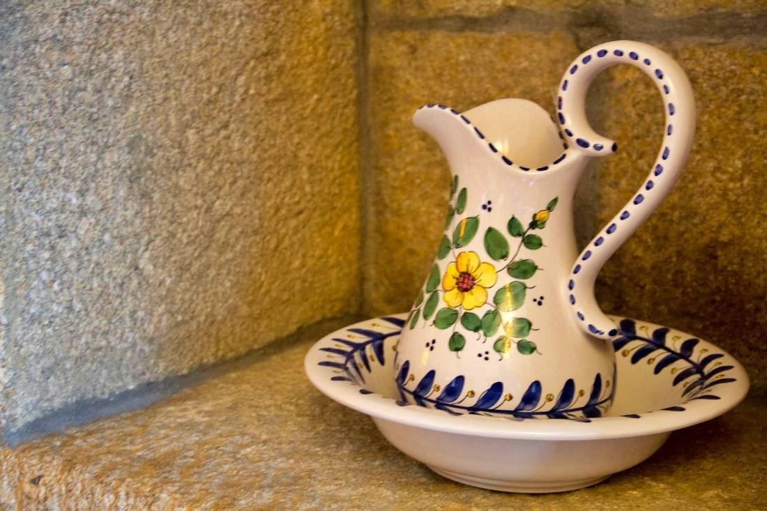 a pitcher with a yellow flower on it sits next to a bowl