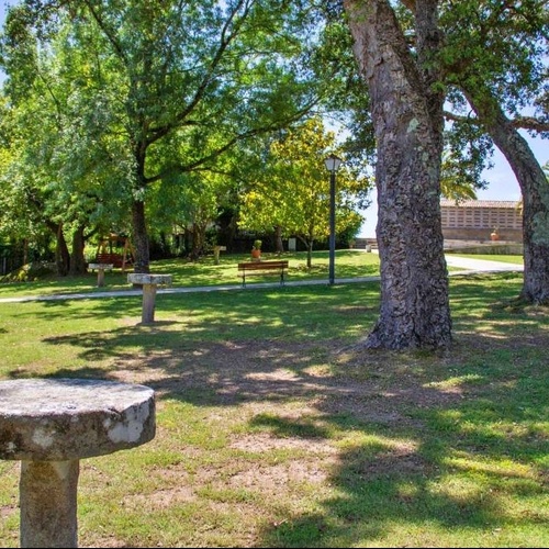 una mesa de piedra en medio de un parque rodeado de árboles