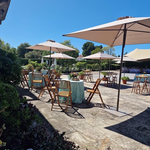 un patio con mesas y sillas y paraguas en un día soleado