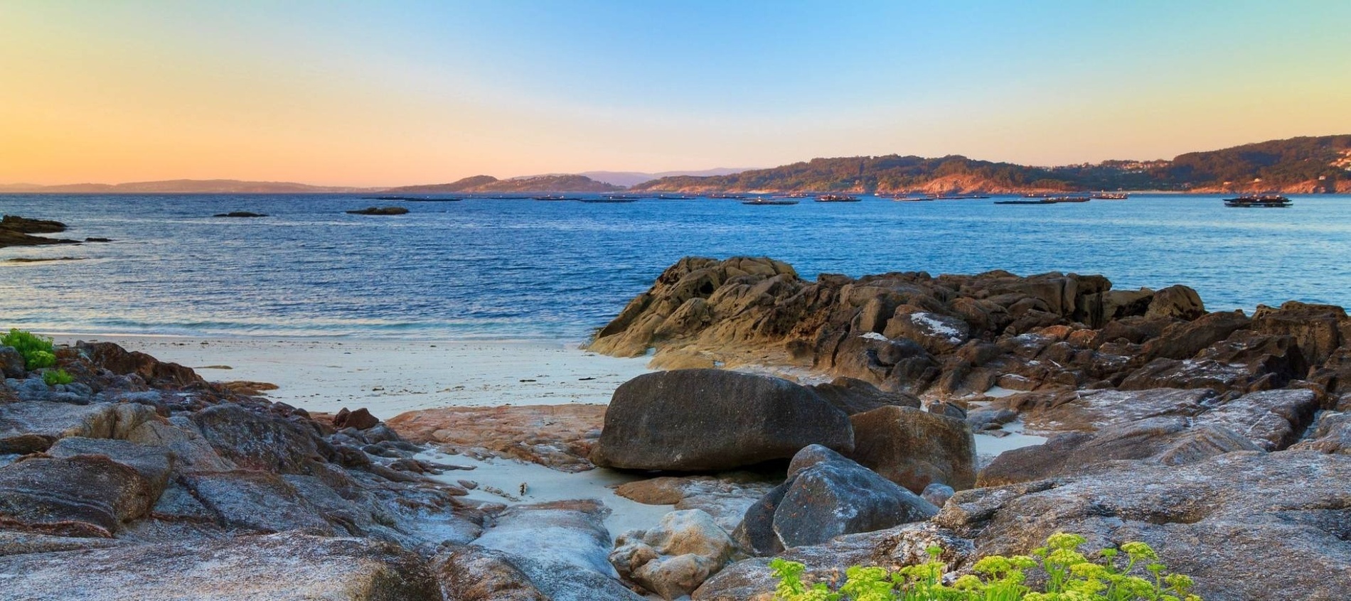 une plage avec des rochers et des montagnes en arrière-plan