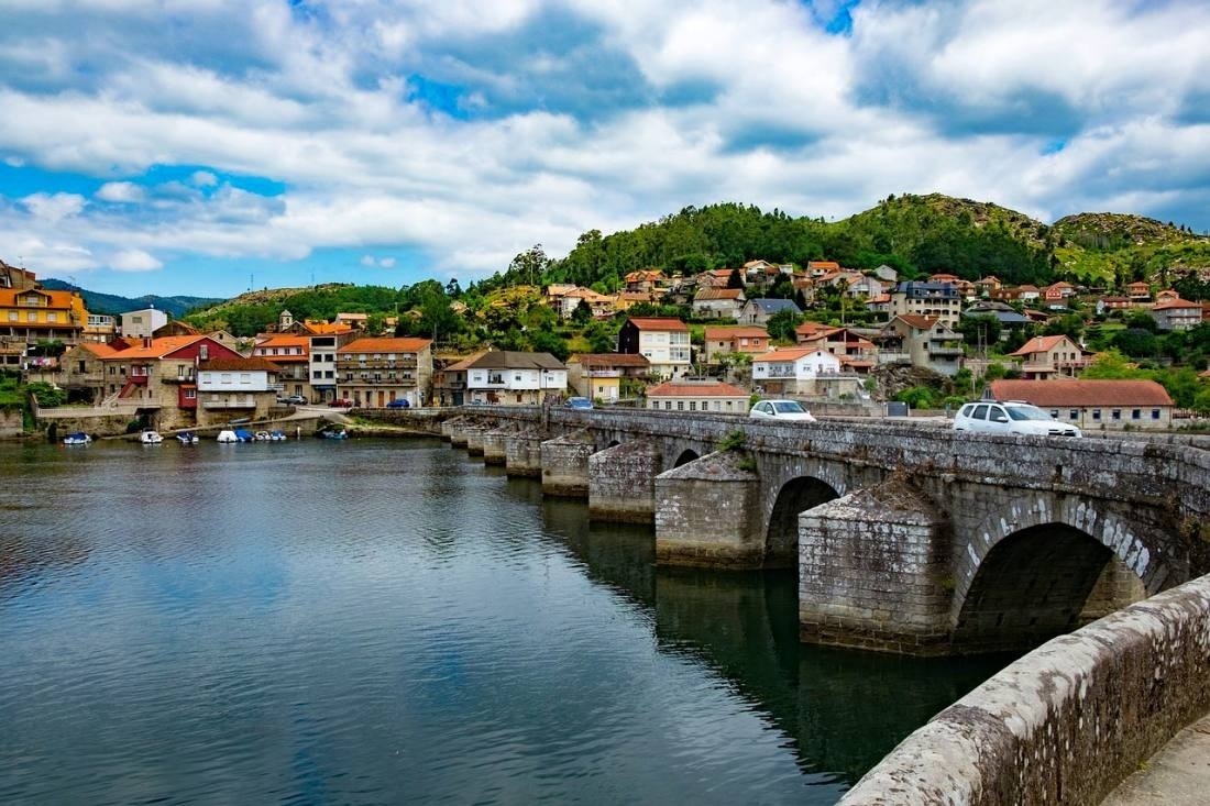 a bridge over a river with a small town in the background