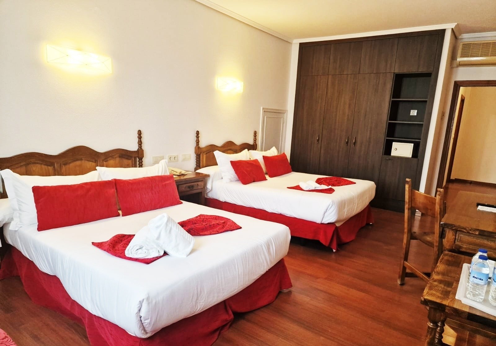 a hotel room with two beds and red pillows