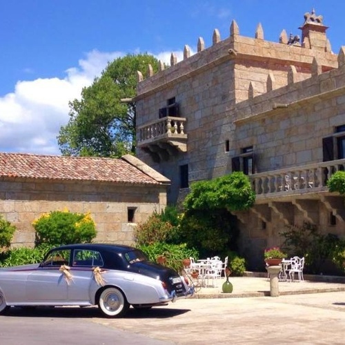 a silver car is parked in front of a stone building