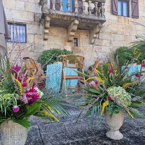 deux vases remplis de fleurs se tiennent devant un balcon