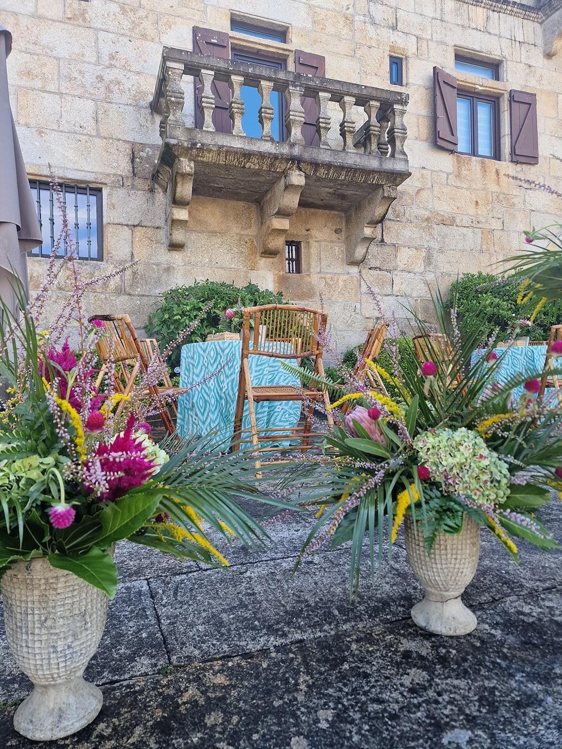 dos macetas llenas de flores están frente a una mesa y sillas