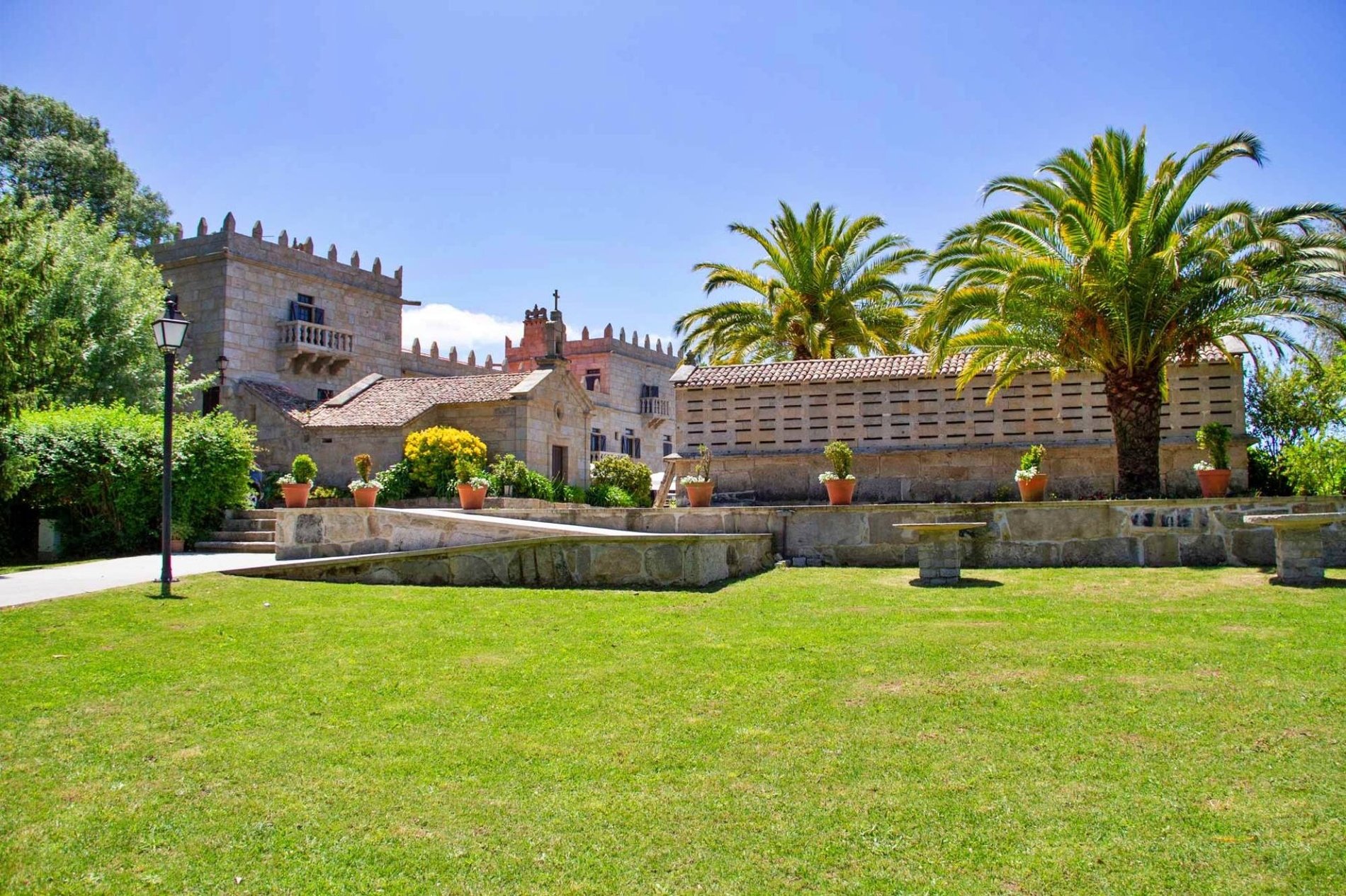un edificio de estilo medieval está rodeado de palmeras y hierba