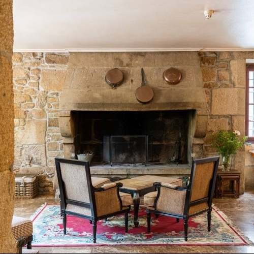 un salon avec des chaises et une cheminée en pierre