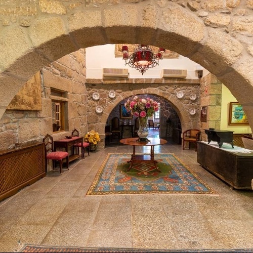 un arco de piedra conduce a una habitación con una mesa y un jarrón de flores