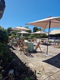 un patio con mesas y sillas y paraguas en un día soleado