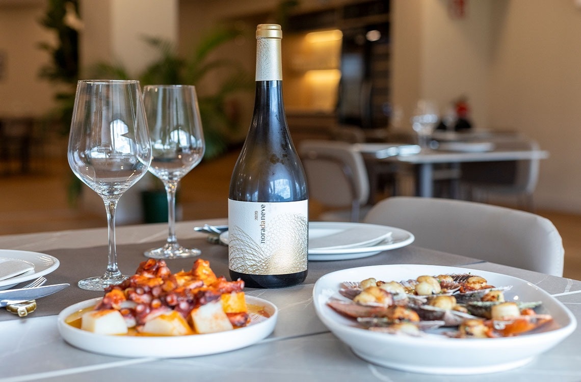 Gourmet seafood and white wine dinner in a sophisticated hotel restaurant setting.