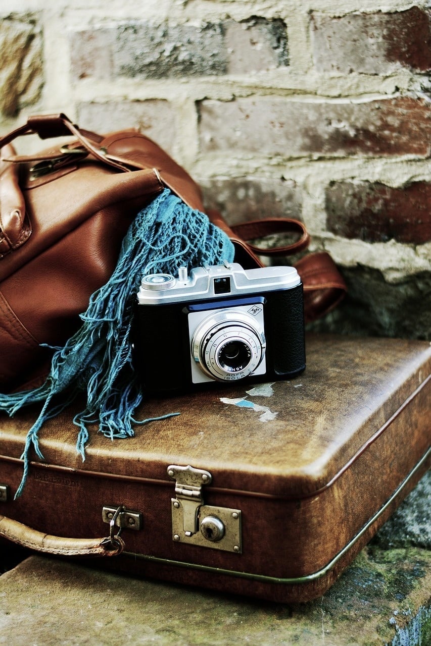 una cámara junto a una maleta para salir de viaje