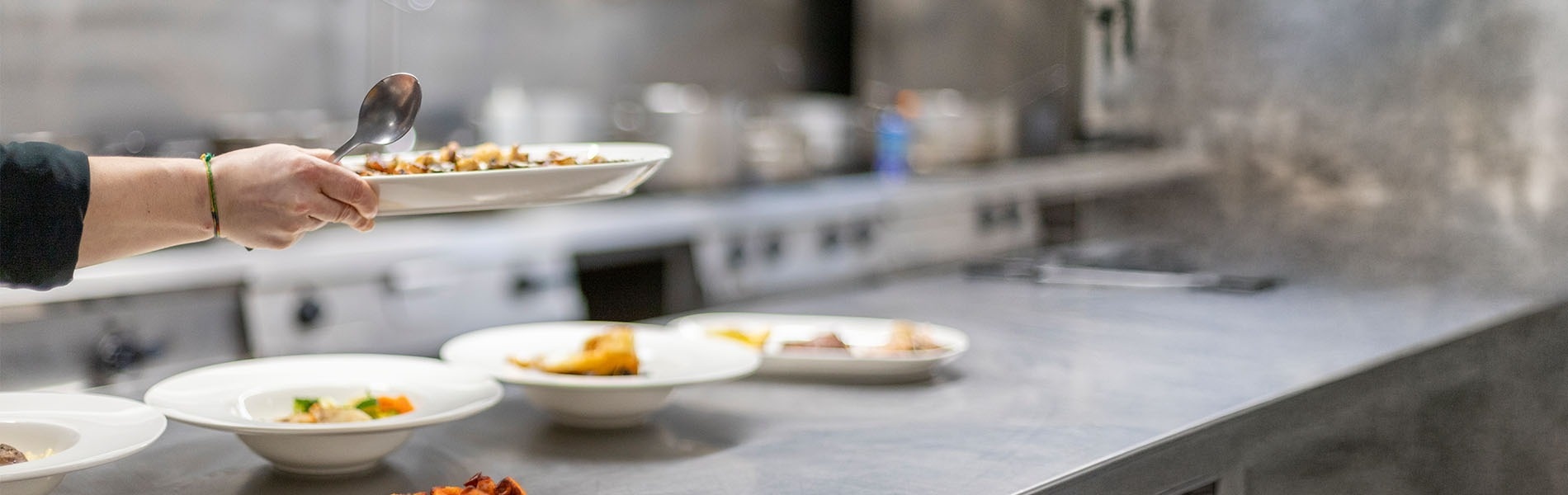 Professional chef carefully plating gourmet dishes in a modern hotel restaurant kitchen.
