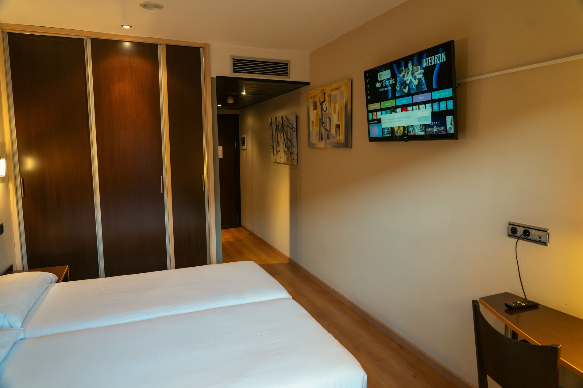 una habitación con una cama y un escritorio con una lámpara y una televisión