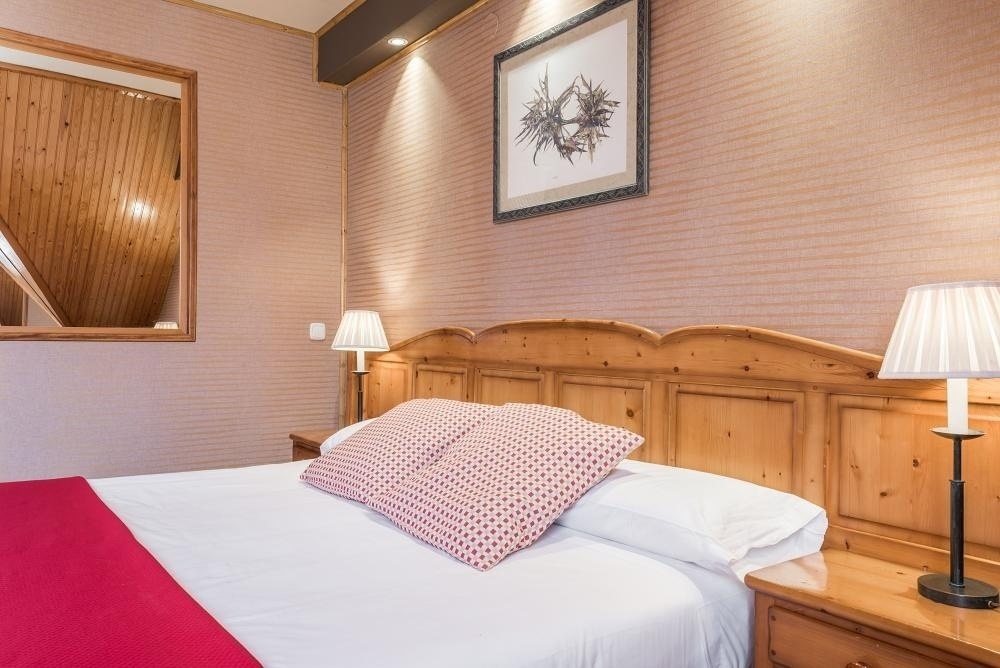 una habitación con una cama y dos lámparas y una pintura en la pared
