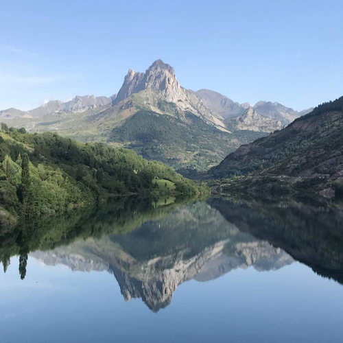 une montagne se reflète dans un lac avec un village en arrière-plan