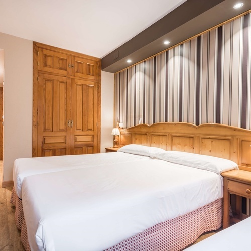 a hotel room with two beds and striped wallpaper