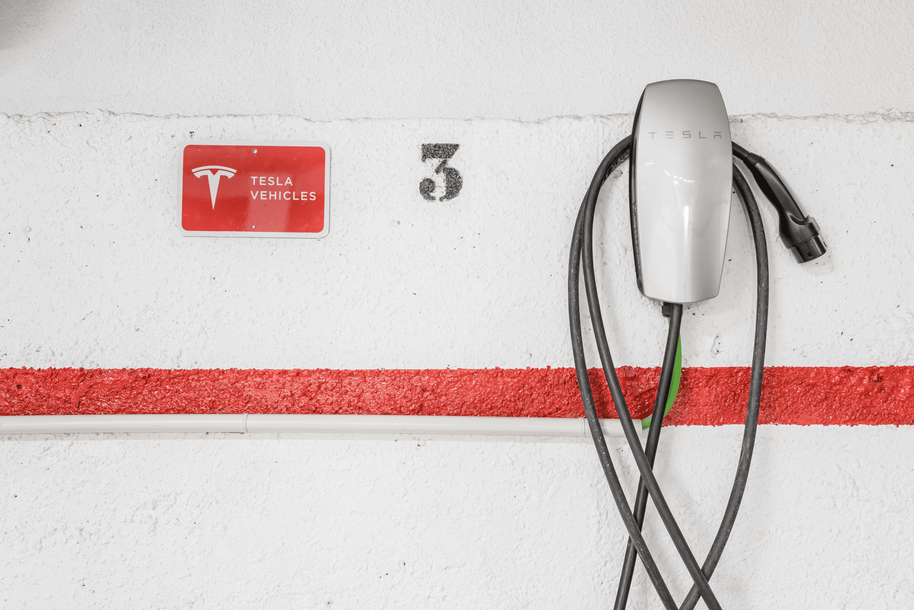 una pared blanca con una señal roja que dice vehículos tesla