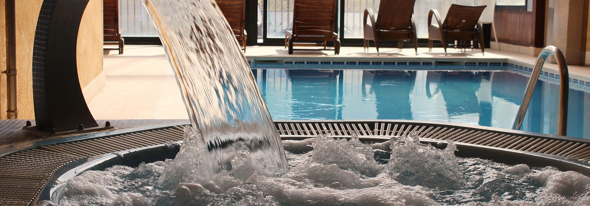 una cascada cae sobre un jacuzzi junto a una piscina