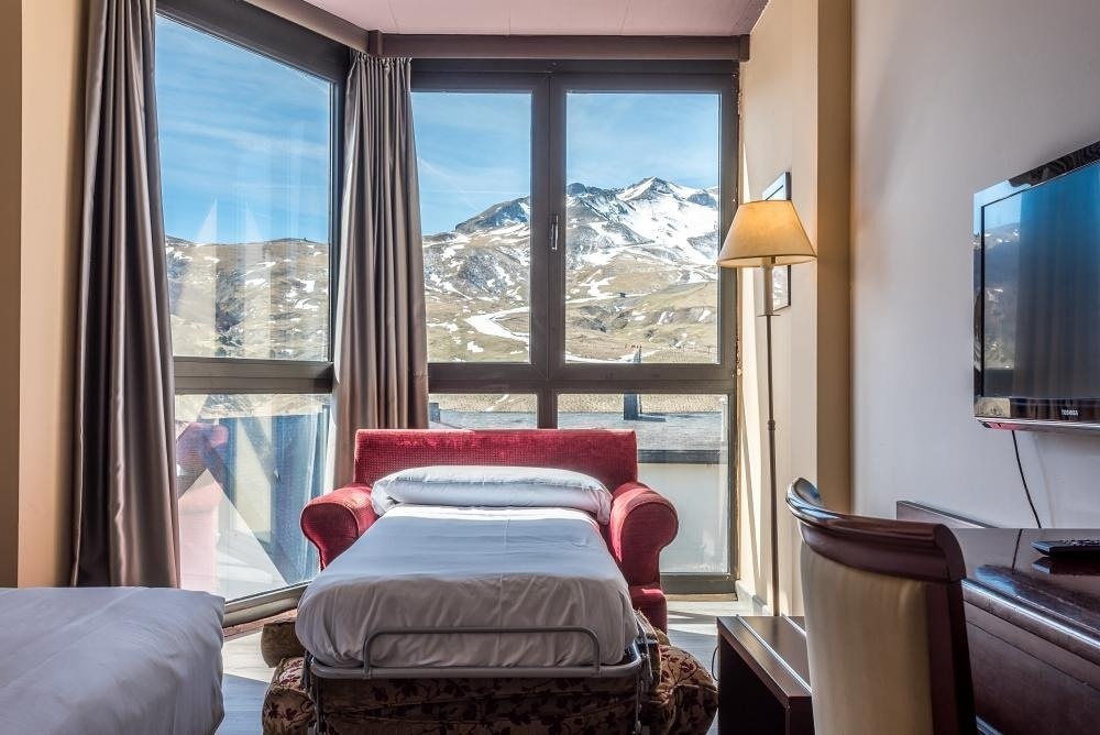 una habitación de hotel con una cama plegable y una televisión