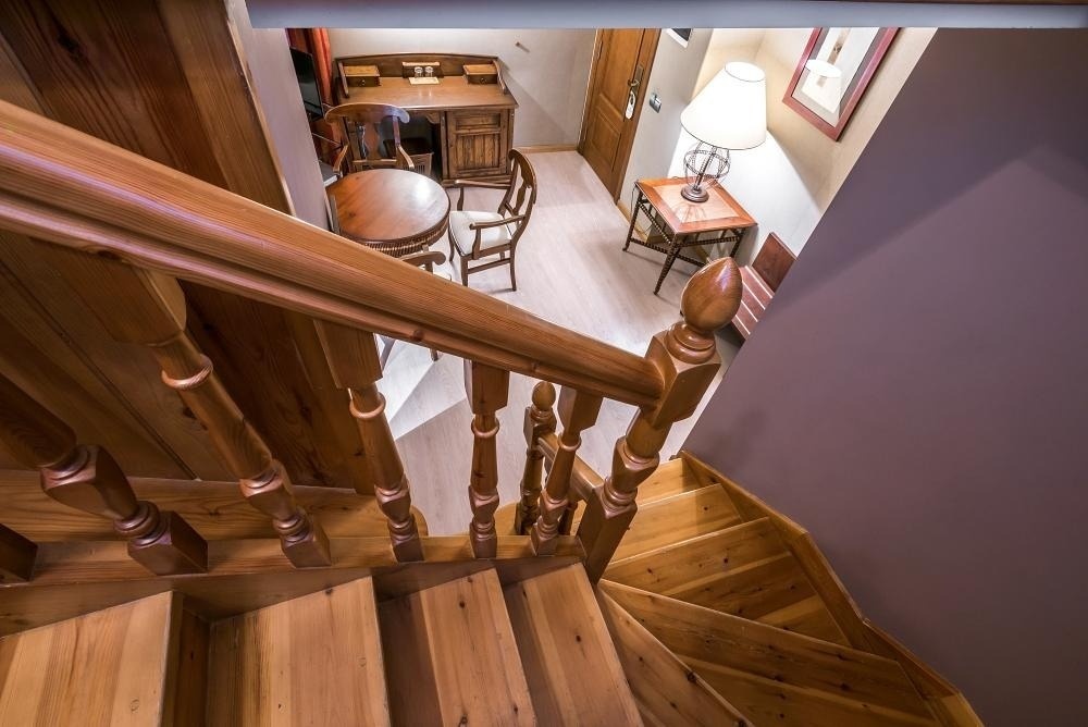 una escalera de madera conduce a una habitación con una mesa y sillas