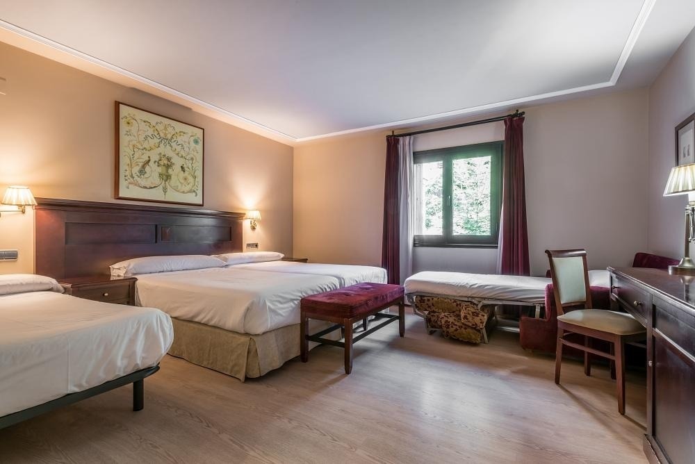 una habitación de hotel con tres camas y una ventana